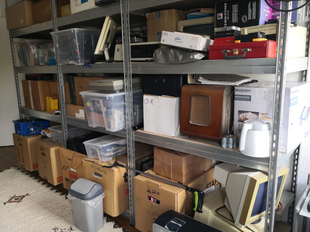 Shelf with lots of moving boxes, plastic boxes, computers, and other stuff. Lower right part.
