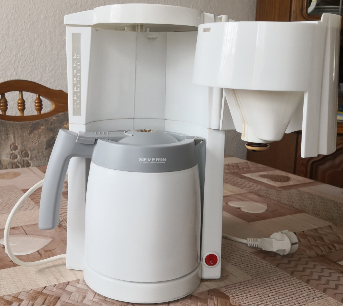 White drip coffee maker on table, not plugged in, brand Severin. One thermos is standing in the machine.