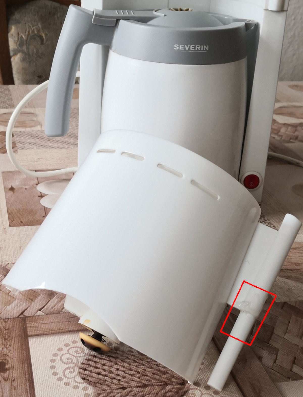 Funnel with the plastic axis removed from coffee maker. Red box around the breaking point.
Residue of hot glue hardly visible on the white plastic